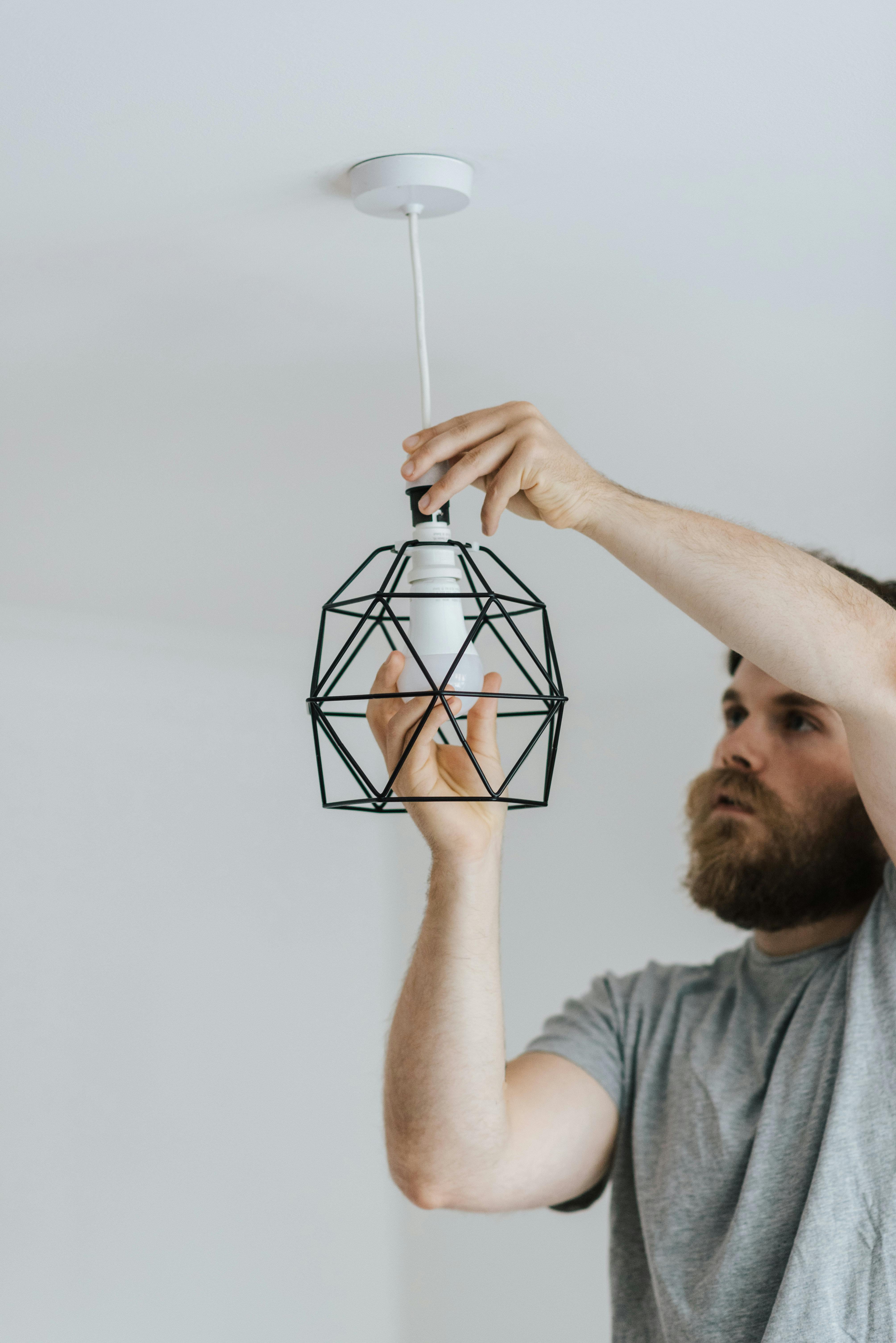 Handyman installing a ceiling fixture inside a polished residential kitchen